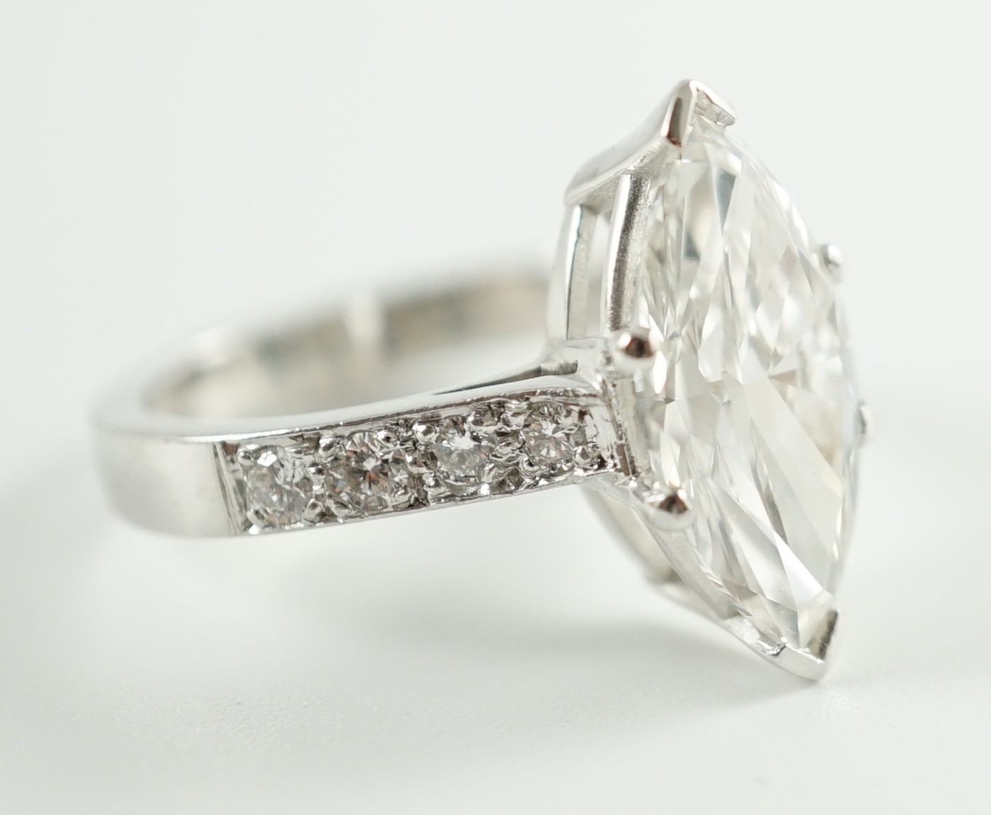 A modern 18ct white gold and single stone marquise diamond set dress ring, with graduated diamond set shoulders, with accompanying WGI report dated 18/6/2021, stating the stone to weigh 3.70ct